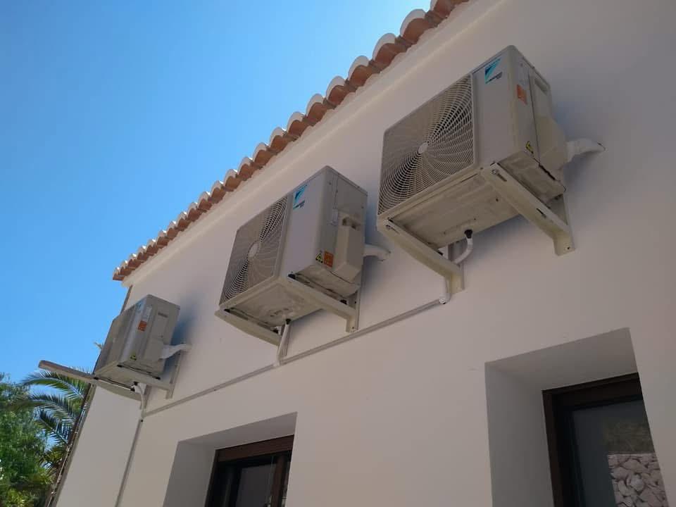 Three outdoor units mounted on a façade beneath the roof